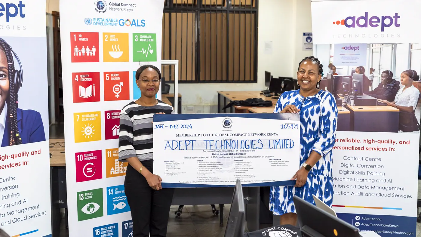 Two members of the Adept team holding the Global Compact Network Kenya membership certificate for Adept Technologies Limited, in front of the Sustainable Development Goals banner