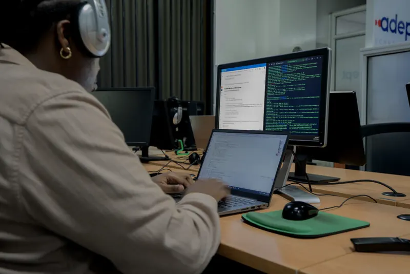 An Adept engineer working at a desk with code on screen